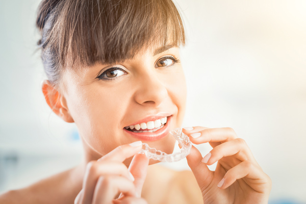 a women holding an upper Invisalign, clear aligner, tray